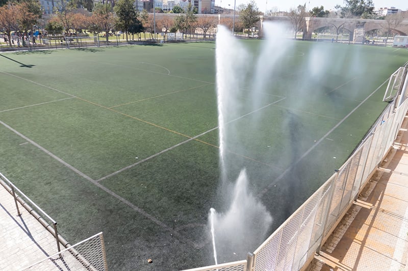 artificial grass soccer field watered with sprinklers